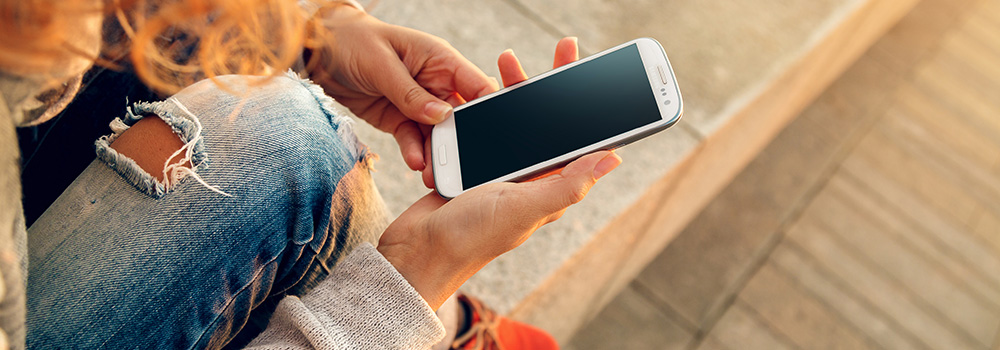 photo of a woman using a mobile device to browse the internet, which is the more common method of browsing in the modern era